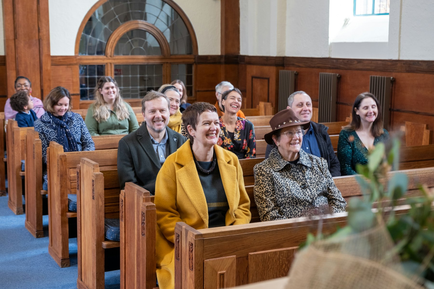 A congregation smiling in wooden pews